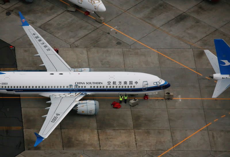 Two employees work on a grounded Boeing 737 MAX aircraft parked at Boeing facilities at Grant County International Airport in Moses Lake