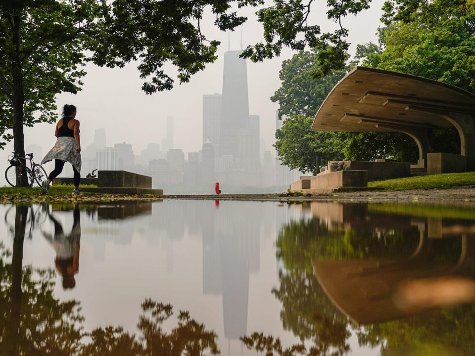 A person walks along the shore of Lake Michigan as the downtown skyline is blanketed in haze from Canadian wildfires Tuesday, June 27, 2023, in Chicago. (AP Photo/Kiichiro Sato)