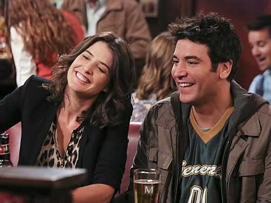 "How I Met Your Mother" characters Robin and Ted laughing, while sitting inside their local bar