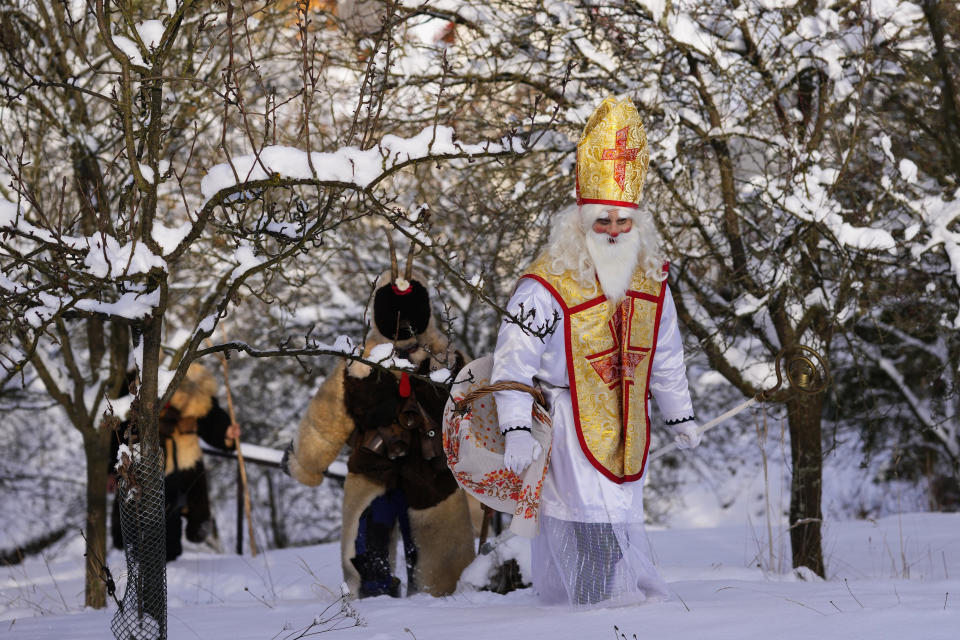 Revelers take part in a traditional St. Nicholas procession in the village of Lidecko, Czech Republic, Monday, Dec. 4, 2023. This pre-Christmas tradition has survived for centuries in a few villages in the eastern part of the country. The whole group parades through village for the weekend, going from door to door. St. Nicholas presents the kids with sweets. The devils wearing home made masks of sheep skin and the white creatures representing death with scythes frighten them. (AP Photo/Petr David Josek)