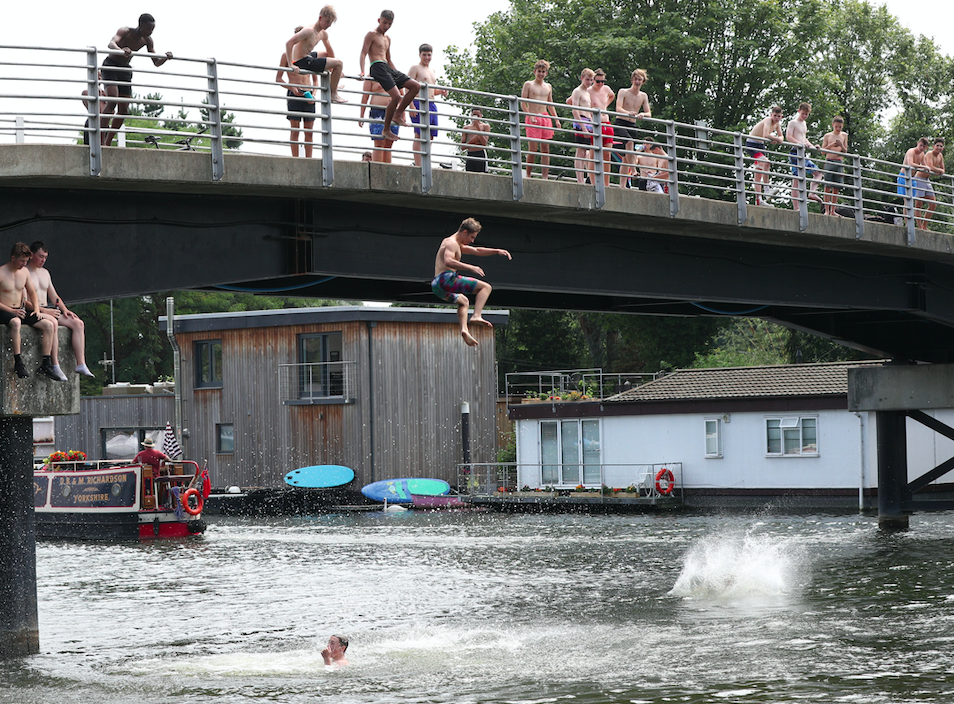 People leap from a bridge at Taggs Island, near Hampton Court, Surrey (PA)