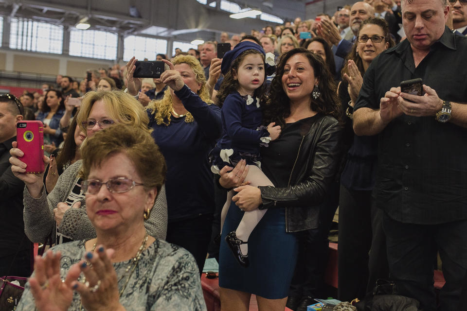 Matias Ferreira's wife, Tiffany, center right, celebrates with her daughter, her mother, bottom left, and her father, top right, during Matias' graduation from the Suffolk County Police Department Academy at the Health, Sports and Education Center in Suffolk, N.Y., Friday, March 24, 2017. Ferreira, a former U.S. Marine Corps lance corporal who lost his legs below the knee when he stepped on a hidden explosive in Afghanistan in 2011, is joining a suburban New York police department. The 28-year-old graduated Friday from the Suffolk County Police Academy on Long Island following 29 weeks of training. (AP Photo/Andres Kudacki)