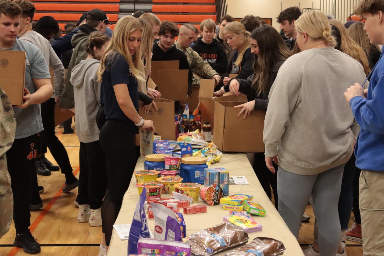 Tecumseh High School students, University of Michigan student-athletes and Michigan Army National Guard members pack care packages to be sent to deployed soldiers during an assembly Friday at Tecumseh High School with the Michigan Army National Guard and University of Michigan student-athletes.