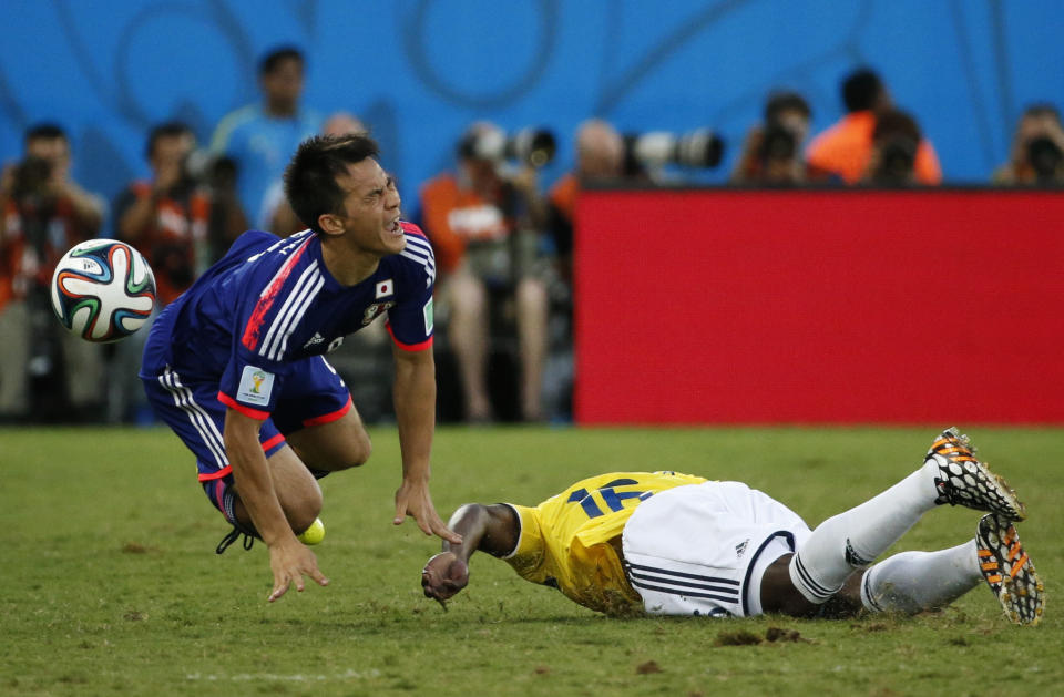 Japan's Shinji Okazaki (L) reacts after a challenge with Colombia's Eder Alvarez Balanta during their 2014 World Cup Group C soccer match at the Pantanal arena in Cuiaba June 24, 2014. REUTERS/Jorge Silva (BRAZIL - Tags: SOCCER SPORT WORLD CUP TPX IMAGES OF THE DAY)