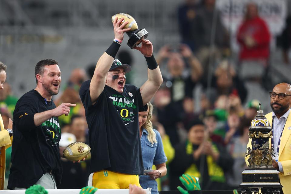 Oregon Ducks quarterback Bo Nix (10) lifts up the offensive MVP trophy after a victory against the Liberty Flames in the 2024 Fiesta Bowl at State Farm Stadium. The Ducks won 45-6.