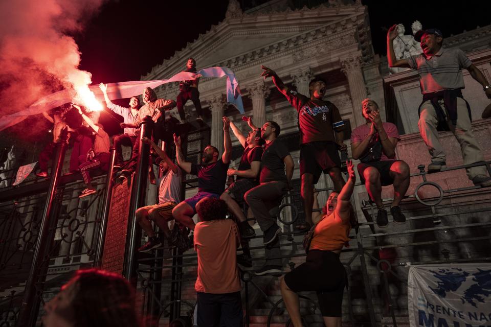 Manifestantes corean consignas antigubernamentales en las rejas que protegen el Congreso Nacional durante una protesta contra las medidas económicas del gobierno, el jueves 21 de diciembre de 2023, en Buenos Aires, Argentina. (AP Foto/Rodrigo Abd)