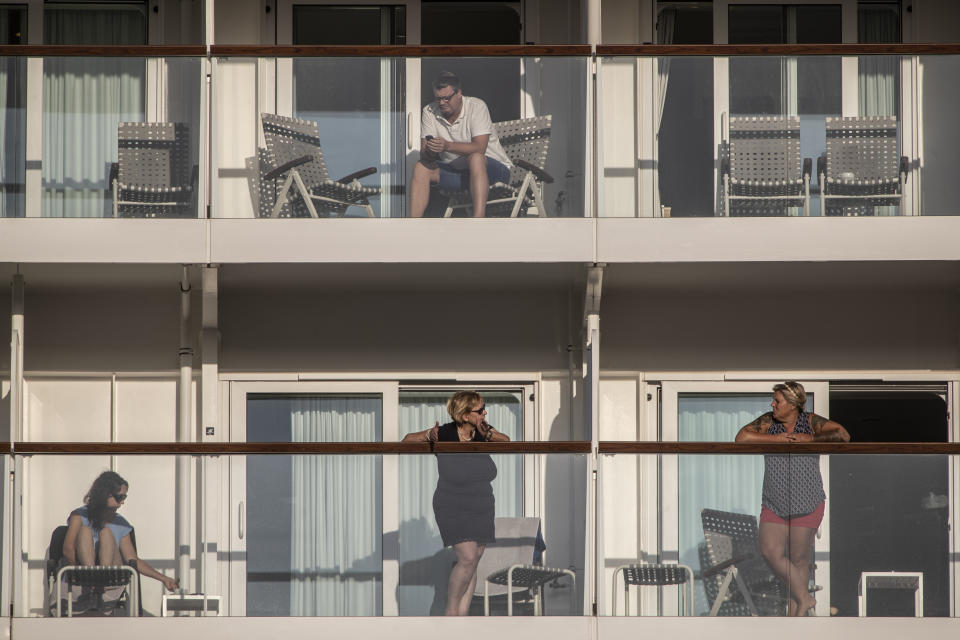 Passengers of the Mein Schiff 6 cruise ship stand outside their cabins as the ship is docked at Piraeus port, near Athens on Tuesday, Sept. 29, 2020. Greek authorities say 12 crew members on a Maltese-flagged cruise ship carrying more than 1,500 people on a Greek islands tour have tested positive for coronavirus and have been isolated on board.(AP Photo/Petros Giannakouris)