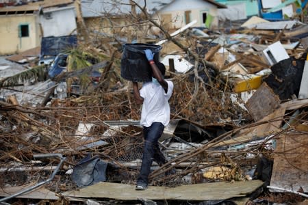 A man carries a container during a search for the dead operation in the destroyed the Mudd neighbourhood after Hurricane Dorian hit the Abaco Islands in Marsh Harbour