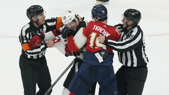 NHL officials attempt to break up a fight between Nico Hischier (13) and Matthew Tkachuk (19). (Photo via AP)