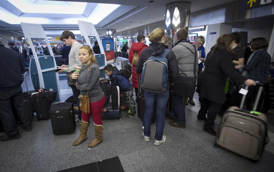 People line up for information about their flights at La Guardia airport in New York January 6, 2014. Winter and accompanying storms are a major issue for U.S. airlines in the first quarter. Airlines typically will proactively cancel flights during a major storm to minimize disruptions. REUTERS/Carlo Allegri (UNITED STATES - Tags: TRANSPORT ENVIRONMENT)