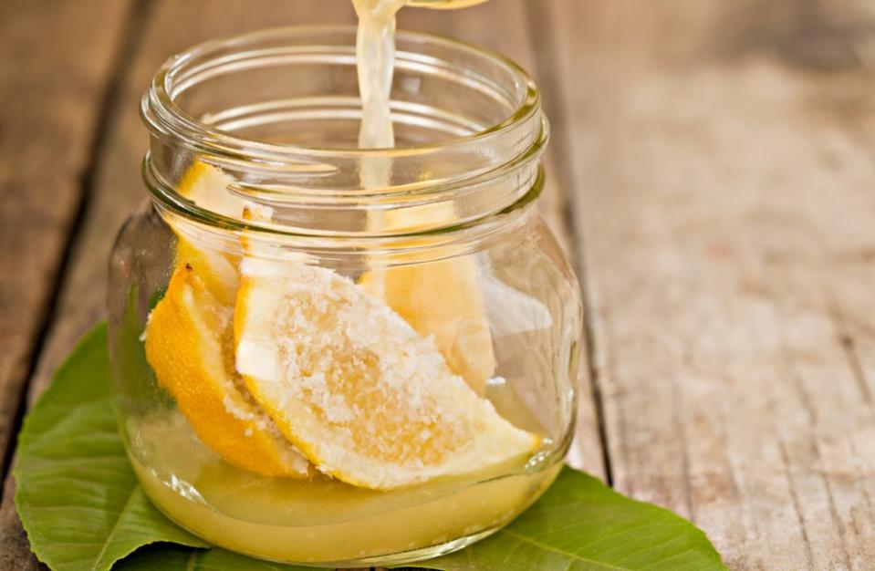 Lemon in clear jar with salt with a leaf under the jar.