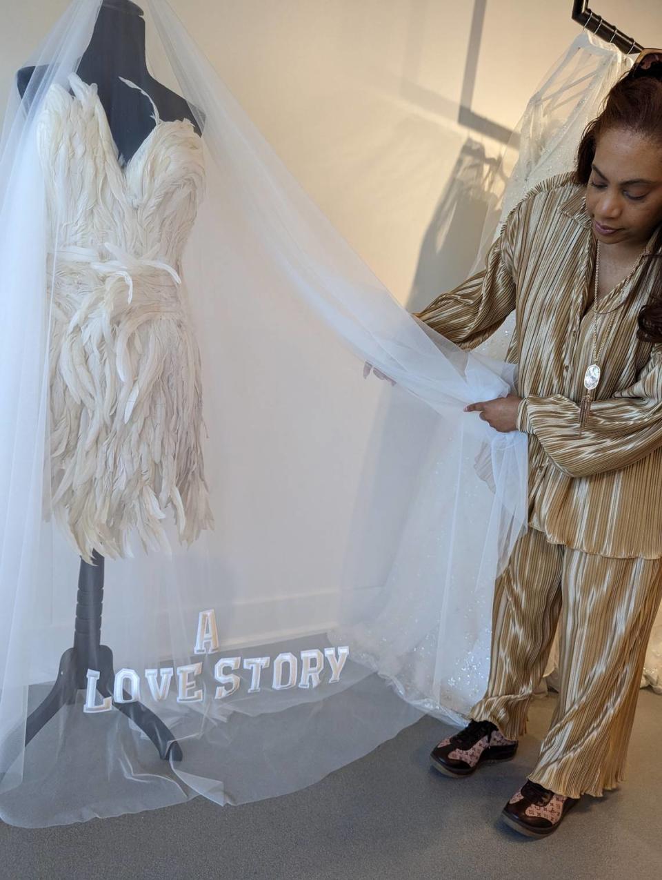 Tracie Mackins hold out a veil showing a veil customized saying “A Love Story” at the Mackins Bridal Boutique in Charlotte.