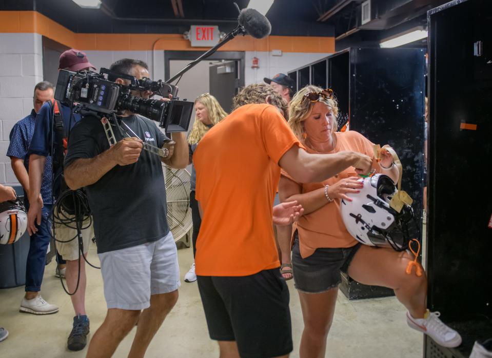 An NFL Films crew records a Washington football player and his mother applying the stripe to his helmet during the annual Mom's Night event Thursday, Aug. 10, 2023 at Babcook Field in Washington.