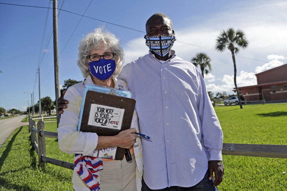 William Freeman, 51, right, poses for a photograph with Arlene Ustin, of the League of Women Voters in Palm Beach County, left, outside of his polling station, Monday, Aug. 10, 2020, in Riviera Beach, Fla. Freeman recently registered to vote after serving three years for grand theft, his fourth prison stint. (AP Photo/Lynne Sladky)