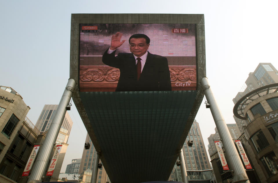 A huge TV screen shows a live broadcast of Li Keqiang, one of the seven newly elected members of the Politburo Standing Committee, waving during a press event, in Beijing Thursday Nov. 15, 2012. The seven-member Standing Committee, the inner circle of Chinese political power, was paraded in front of assembled media on the first day following the end of the 18th Communist Party Congress. (AP Photo/Andy Wong)