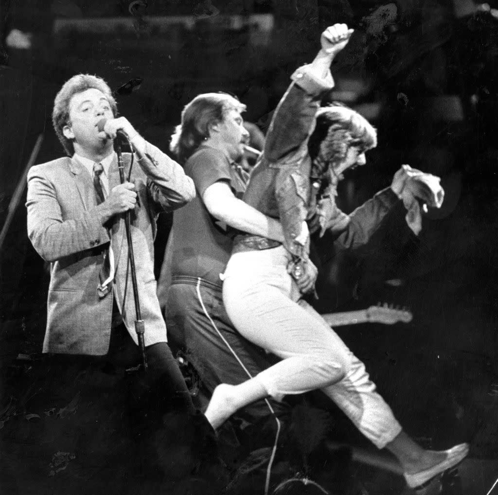 singer billy joel on stage, as a fan is being removed, september 21, 1984