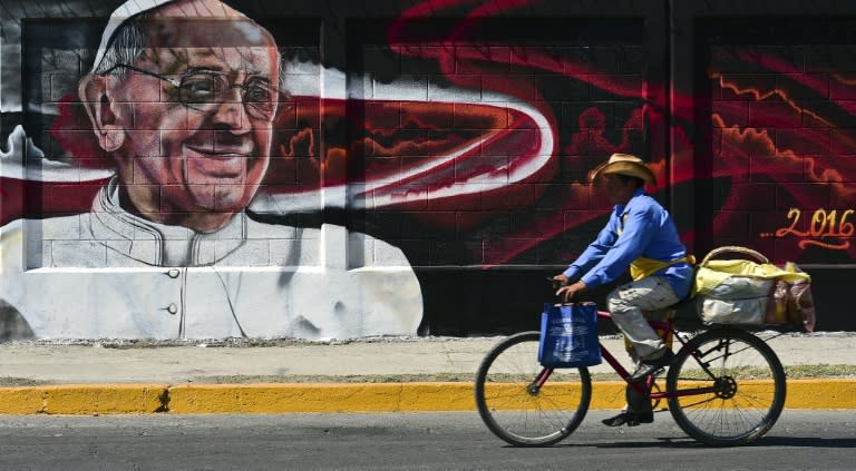 A man rides a bicycle past a poster welcoming Pope Francis to Ecatepec, Mexico on February 5, 2016