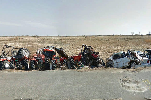 The wreckage of tractors and other vehicles line a road near Namie's shore.