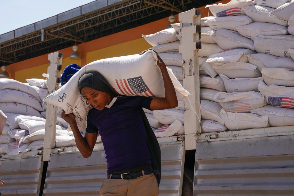 Volunteers unload sacks of wheat flour that were part of an aid delivery.