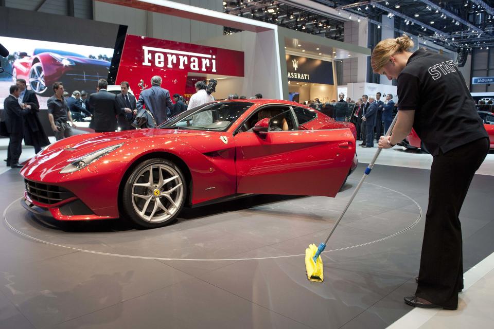 A woman cleans the floor in front of the new Ferrari F12 Berlinetta during the press day at the Geneva International Motor Show in Geneva, Switzerland, Tuesday, March 6, 2012. The Motor Show will open its gates to the public from March 8 to 18, presenting more than 260 exhibitors and more than 180 world and European premieres. (AP Photo/Keystone, Sandro Campardo)