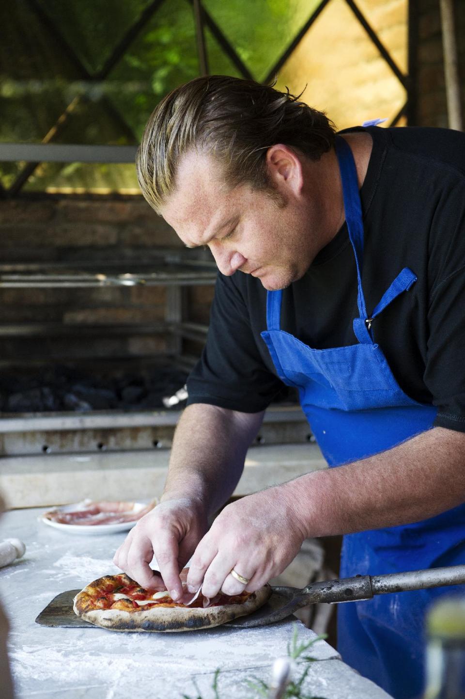 This book cover image released by Ballantine Books shows Michael White preparing a pizza, a dish from his book "Classico E Moderno: Essential Italian Cooking," with Andrew Friedman. White is the chef and owner of Marea restaurant in New York. (AP Photo/Ballantine Books, Evan Sung)