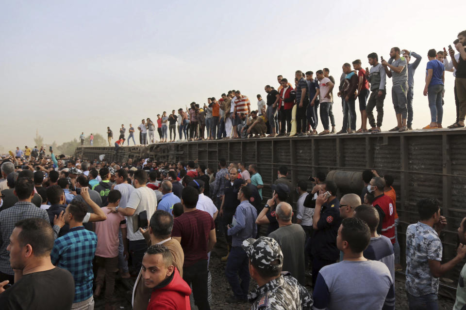 People gather at the site where a passenger train derailed injuring at least 100 people, in Banha, Qalyubia province, Egypt, Sunday, April 18, 2021. At least eight train wagons ran off the railway, the provincial governor's office said in a statement. (AP Photo/Fadel Dawood)