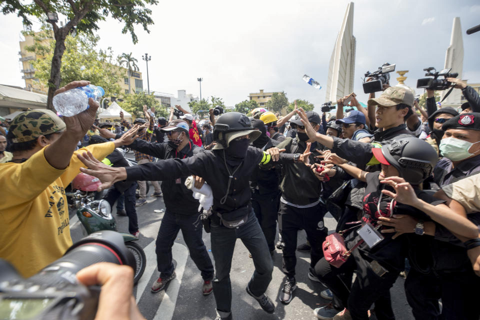 Supporters of the the monarchy, left, and pro-democracy supporters scuffle at a rally near the Democracy Monument in Bangkok, Thailand, Wednesday, Oct. 14, 2020. Thousands of anti-government protesters gathered Wednesday for a rally at Bangkok’s Democracy Monument being held on the anniversary of a 1973 popular uprising that led to the ousting of a military dictatorship, amid a heavy police presence and fear of clashes with political opponents. (AP Photo/Wason Wanichakorn)