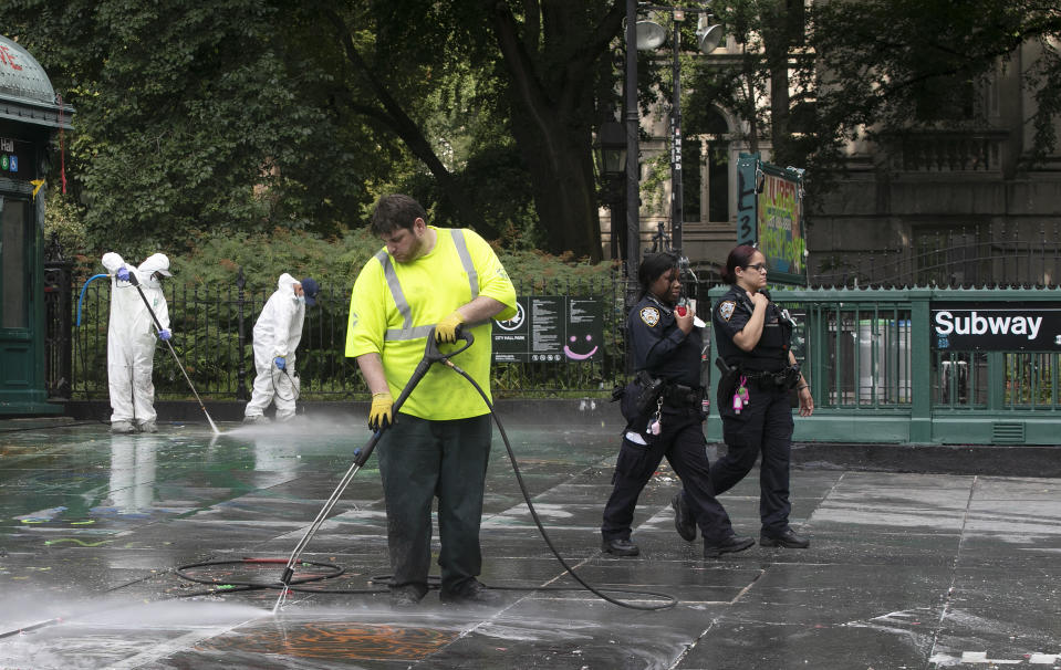 City workers power wash a park adjacent to City Hall, Wednesday, July 22, 2020, in New York. Police in riot gear cleared a month-long encampment of protesters and homeless people from the park adjacent to New York's City Hall earlier in the morning. (AP Photo/Mark Lennihan)