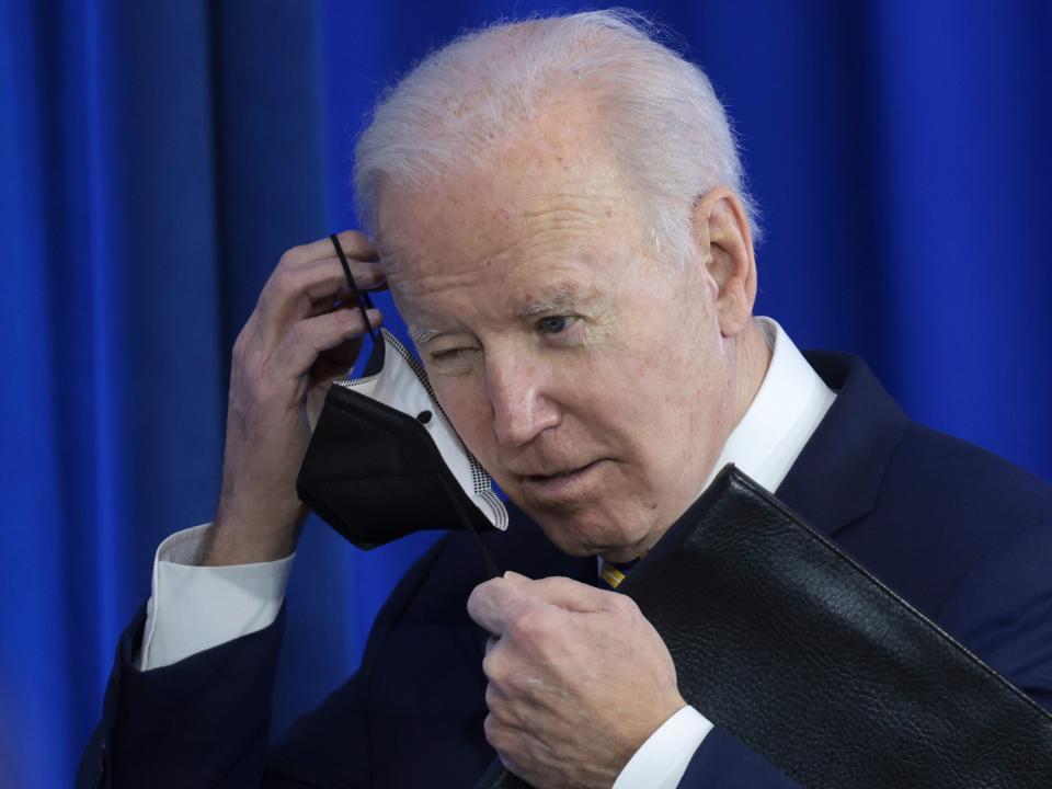 Joe Biden removes his mask before speaking at an event.