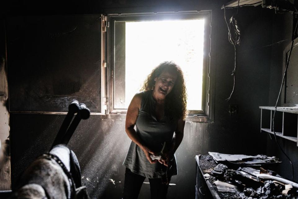 Kibbutz Nir Oz resident Hadas Kalderon, whose children have been taken hostage, and her mother and niece killed, breaks down in tears while looking through the burnt out home of her late mother