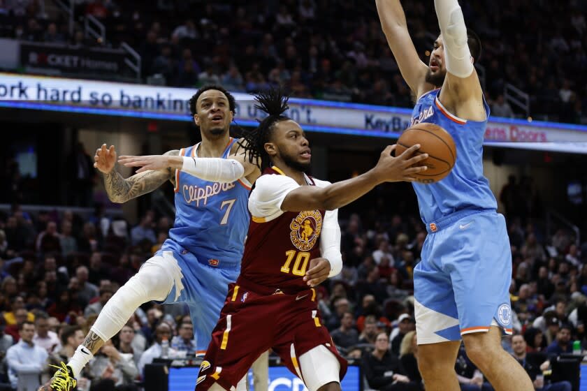 Cleveland Cavaliers' Darius Garland (10) passes against Los Angeles Clippers' Ivica Zubac (40) and Amir Coffey (7) during the second half of an NBA basketball game, Monday, March 14, 2022, in Cleveland. (AP Photo/Ron Schwane)