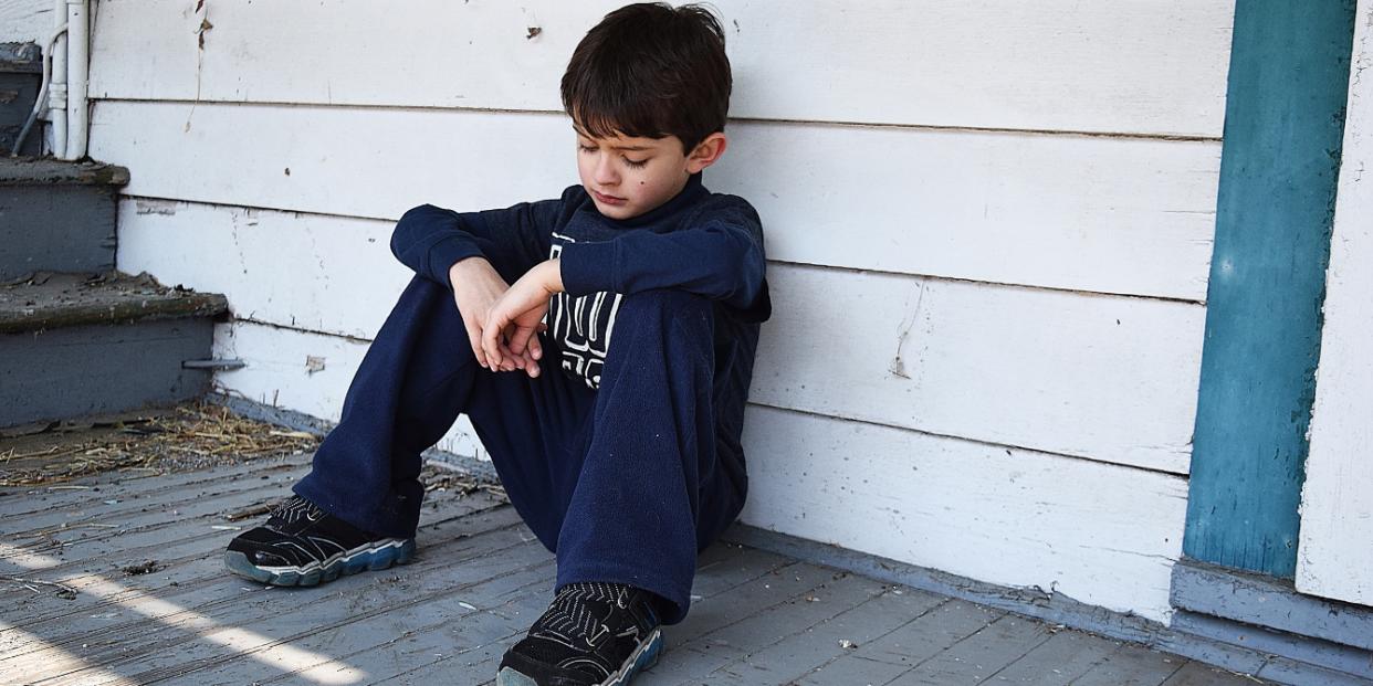 sad child sitting in front of home affordable housing