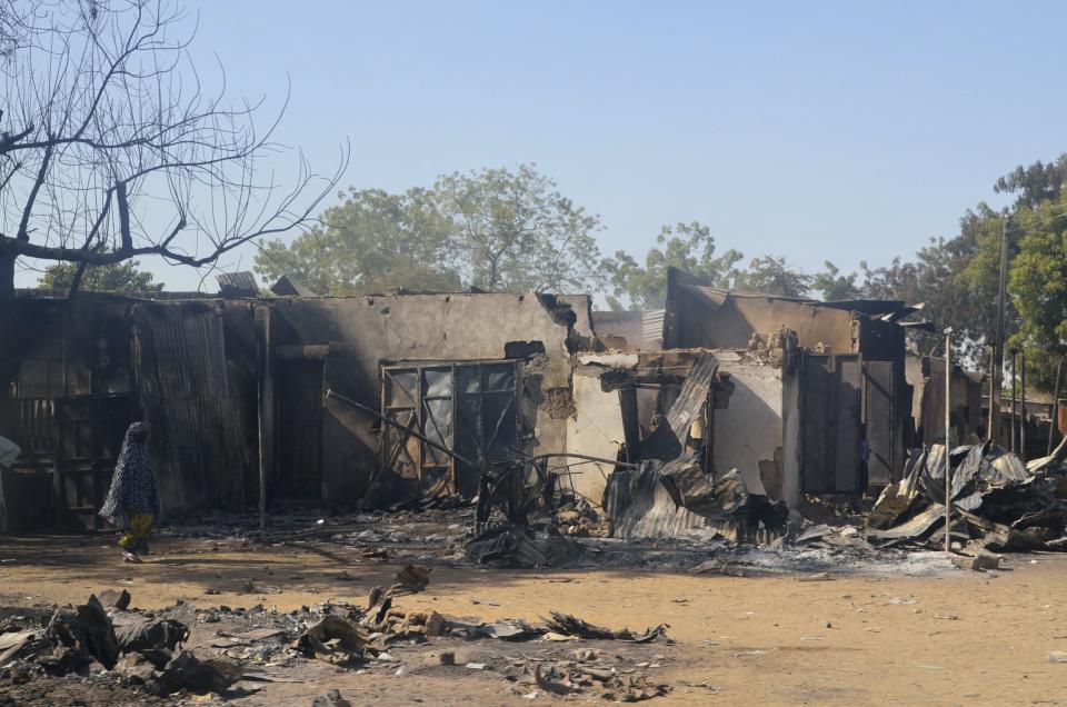 A woman walks past homes destroyed by Boko Haram militants in Bama, Borno State, February 20, 2014. Gunmen from Nigeria's Islamist Boko Haram sect killed 98 people in the northeastern town of Bama on Wednesday, residents there said after burying their folk, more than double the figure given by police a day earlier. Gunmen stormed the town in the early hours of Wednesday, firing on a school, shooting or burning to death dozens of people and trashing the palace of a traditional ruler of one of West Africa's oldest Islamic kingdoms. Police had initially put the death toll at 47. Picture taken February 20, 2014. REUTERS/Stringer (NIGERIA - Tags: MILITARY CIVIL UNREST POLITICS)