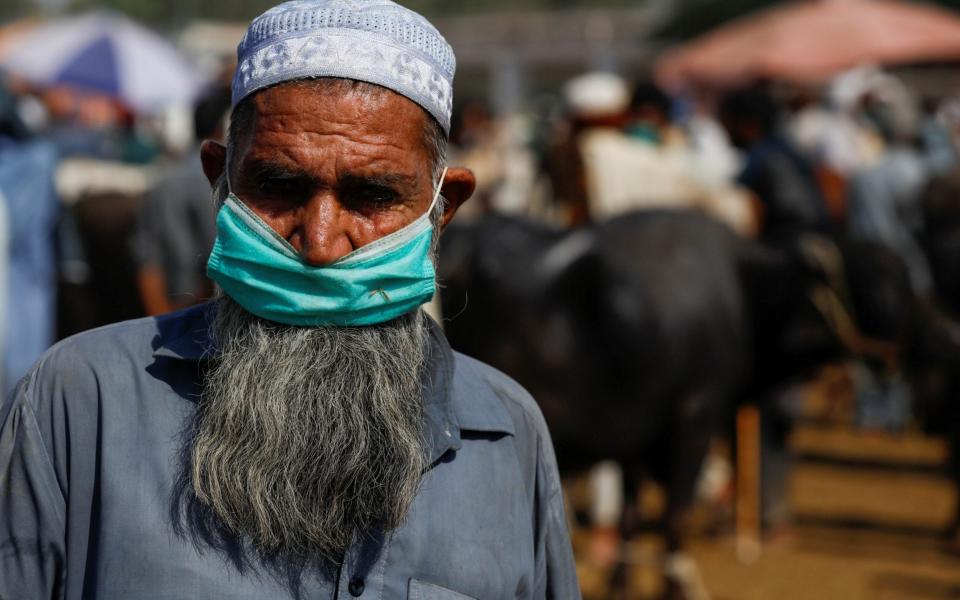 A man wears a protective mask as he sells cows for the upcoming Eid Al Adha sacrifice, at the cattle market - Reuters