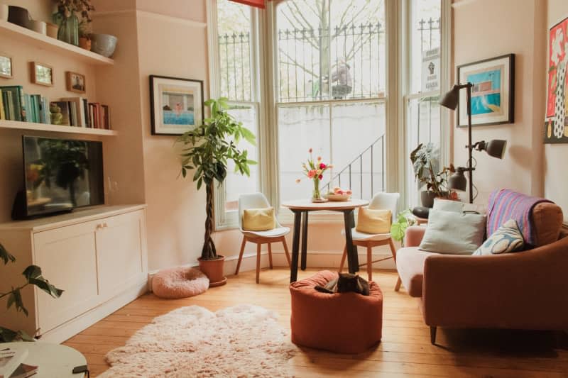 A cat lays on an ottoman in a living room.