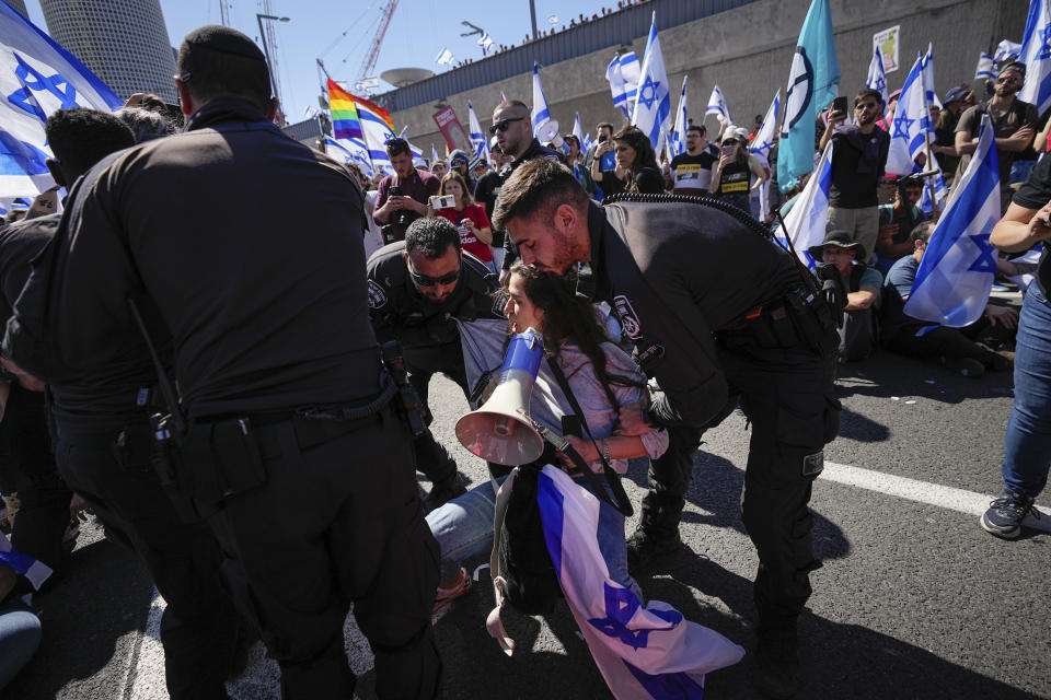 Israeli police officers disperse demonstrators blocking a highway during protest against plans by Prime Minister Benjamin Netanyahu's government to overhaul the judicial system in Tel Aviv, Israel, Thursday, March 16, 2023. (AP Photo/Ohad Zwigenberg)