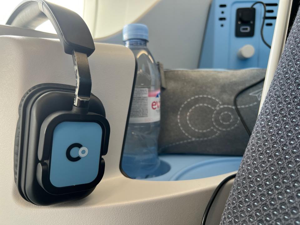 The nook to the left of the author's lounger, containing a pair of headphones, a water bottle, and an amenity kit.