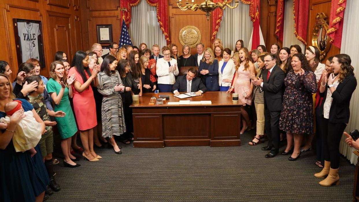 Florida Sen. Erin Grall, R-Fort Pierce, (center left, in white) looks over the right shoulder of Gov. Ron DeSantis as he signs Senate Bill 300, also called the Heartbeat Protection Act, into law on April 13 in Tallahassee. The controversial legislation forbids the abortion of a fetus older than 6 weeks.