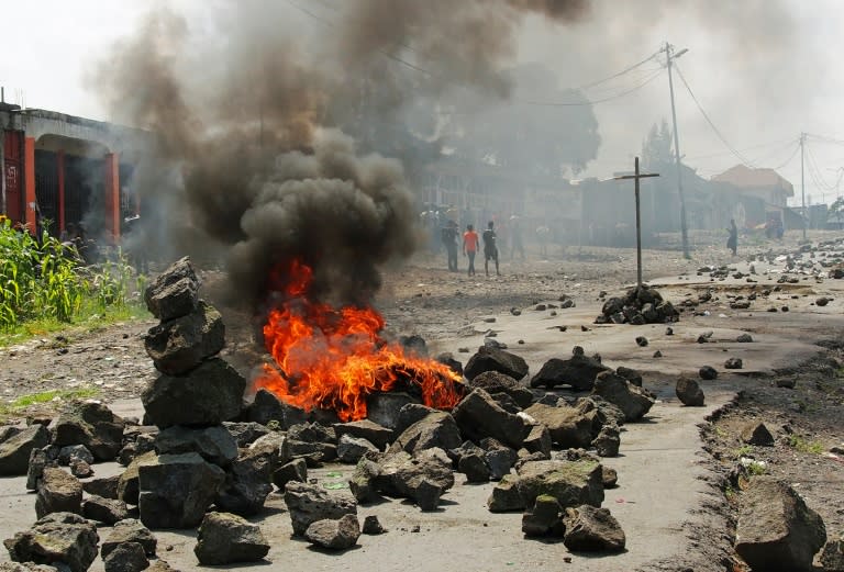 People walk past a burning barricade during a protest against President Joseph Kabila, in Goma on May 26, 2016