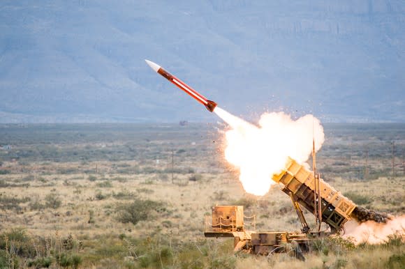 A Patriot missile blasting off over a deserted field