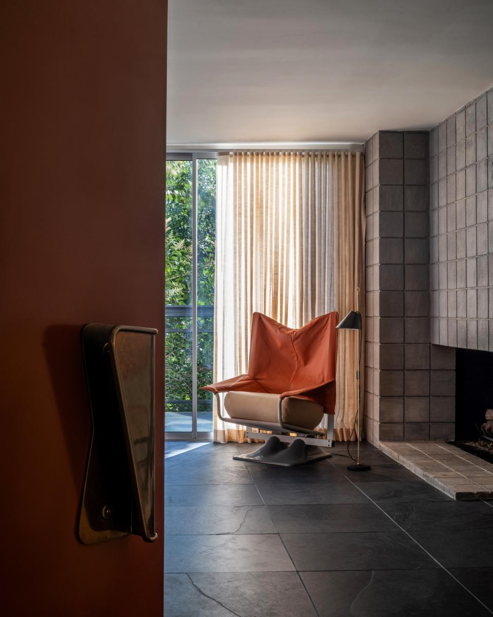 A scarlet front door, enlivened in Farrow & Ball’s Picture Gallery Red and a vintage brass Gio Ponti handle, opens to reveal one end of the living room. A restored 1970s AeO chair, dressed in a bright orange leather from Maharam Textiles, sits by the fireplace in the company of Azucena’s Monachella Floor Lamp by Luigi Caccia Dominioni.