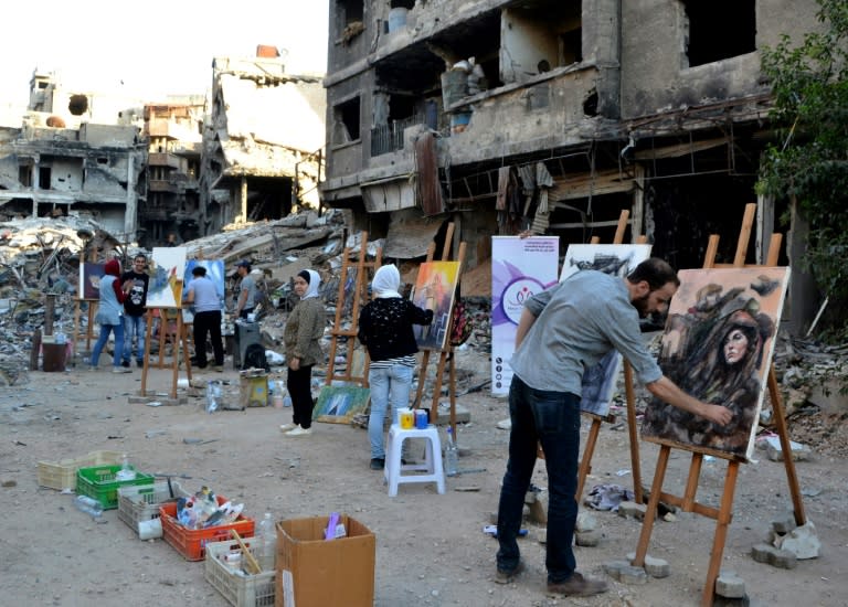 Artists paint in the Yarmuk Palestinian refugee camp on the southern outskirts of the capital Damascus on August 15, 2018
