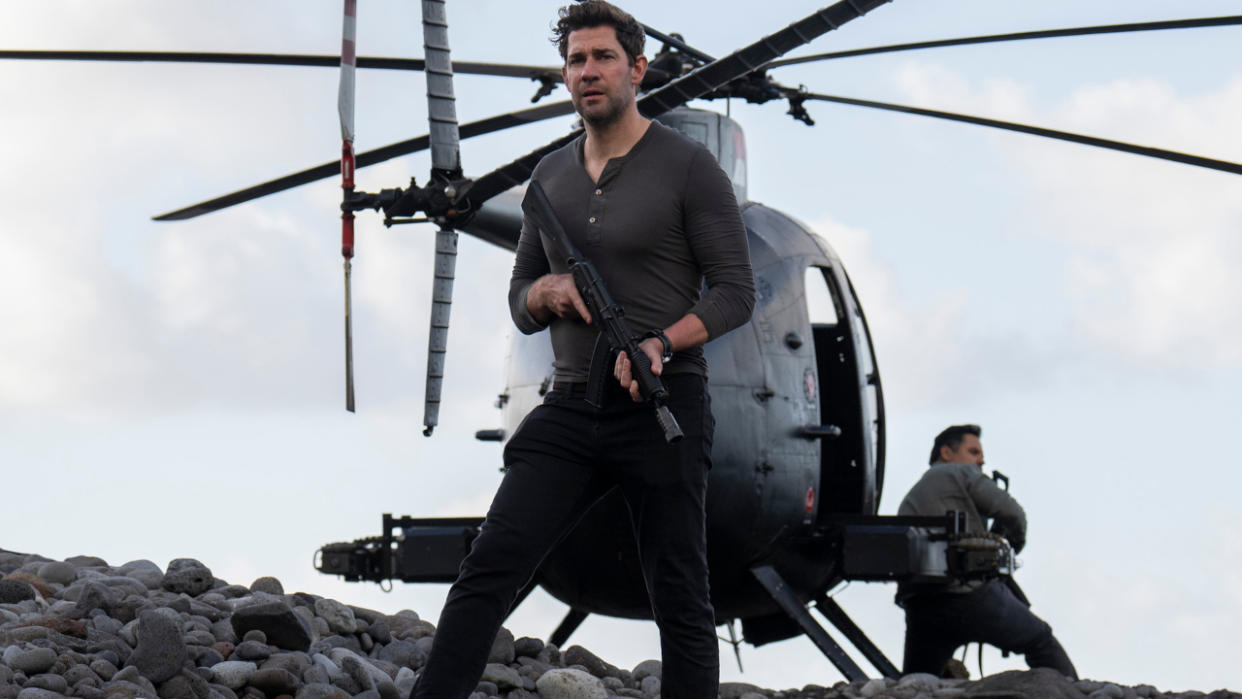  John Krasinski stands armed in front of a helicopter in Tom Clancy's Jack Ryan. 