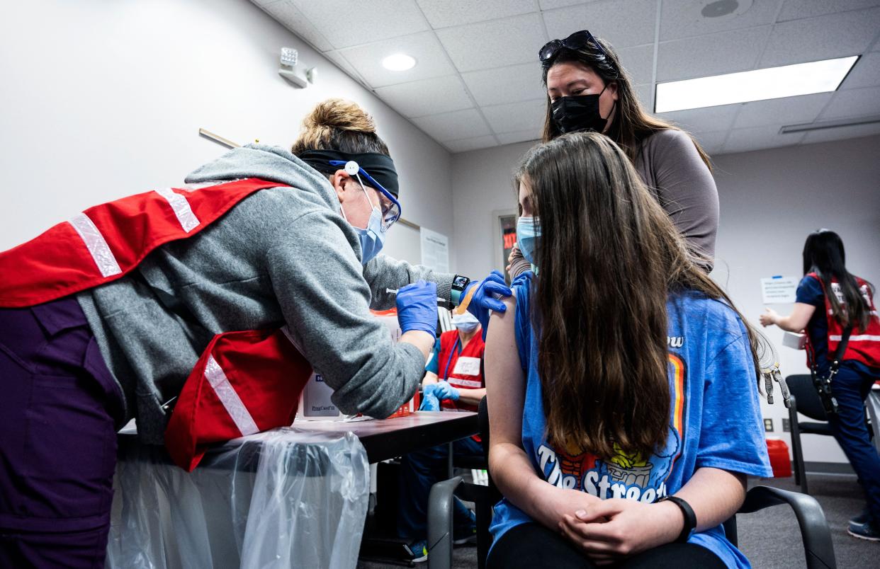 A mother looks on as her daughter gets a Covid-19 vaccination in Virginia on 13 May, 2021. A new poll has found that a quarter of adults in the United States do not intend to get their children vaccinated against Covid-19 (AFP via Getty Images)