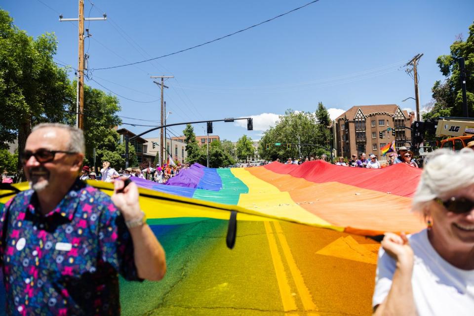 The LGBTQ Pride flag is seen past Scott and Lynne Barrett, during the 2023 Utah Pride Parade in downtown Salt Lake City on Sunday.