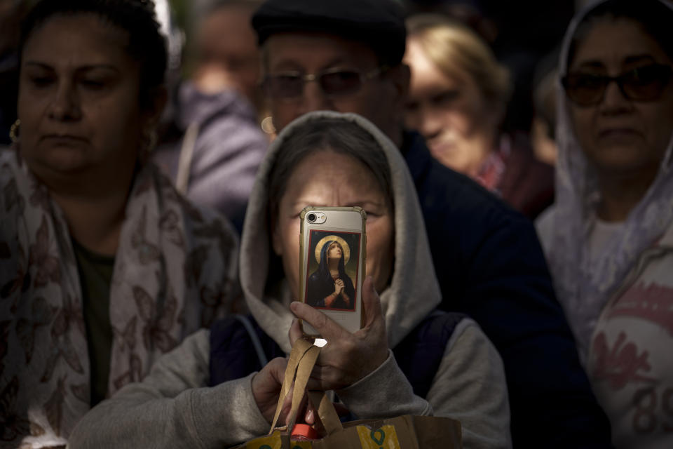 A woman takes pictures on a mobile phone as priests walk during the Saint Dimitrie Bassarabov, patron saint of the Romanian capital, procession, in Bucharest, Romania, Tuesday, Oct. 24, 2023. Romanian Orthodox worshipers celebrate Saint Dimitrie Bassarabov, with thousands waiting in line for long hours to touch the remains of the saint. (AP Photo/Vadim Ghirda)