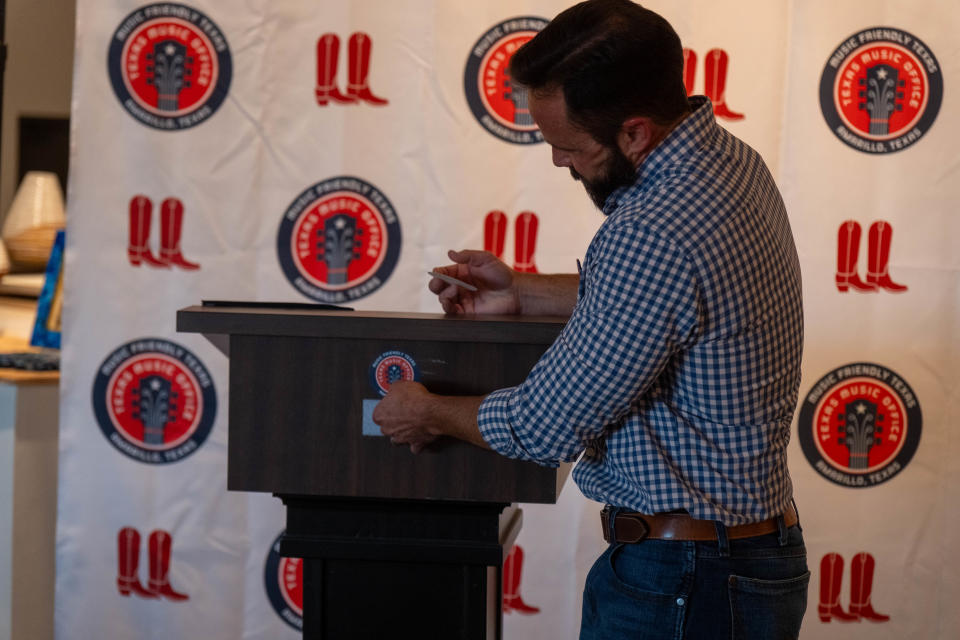 Amarillo Mayor Cole Stanley puts on the lectern a sticker with an Amarillo Music Friendly designation Monday at Arts in the Sunset in Amarillo.