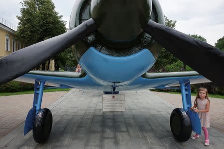 A girl stands under a Soviet-style military airplane at Kremlin in Nizhny Novgorod, Russia, June 30, 2018. REUTERS/Damir Sagolj