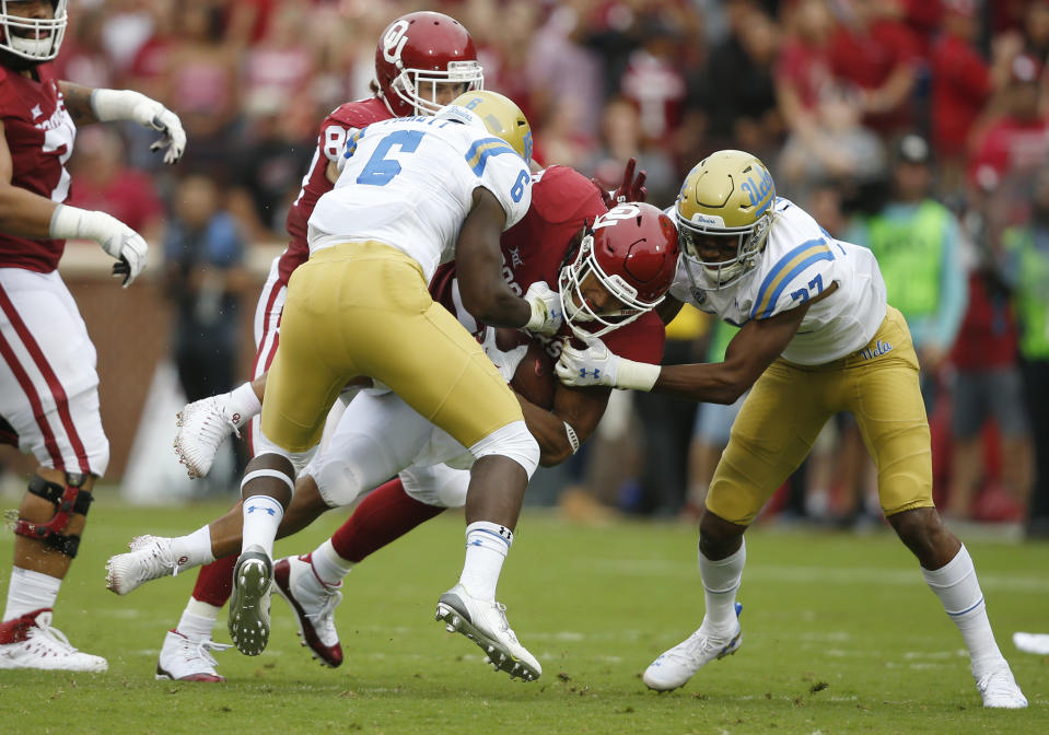 Oklahoma running back Rodney Anderson, center, is tackled by UCLA defensive back Adarius Pickett (6) and defensive back Quentin Lake (37) in the first quarter of an NCAA college football game in Norman, Okla., Saturday, Sept. 8, 2018. (AP Photo/Sue Ogrocki)