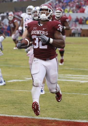 Oklahoma's Samaje Perine (32) sprints into the end zone with a touchdown ahead of Kansas' Ben Heeney.(AP Photo/Sue Ogrocki)